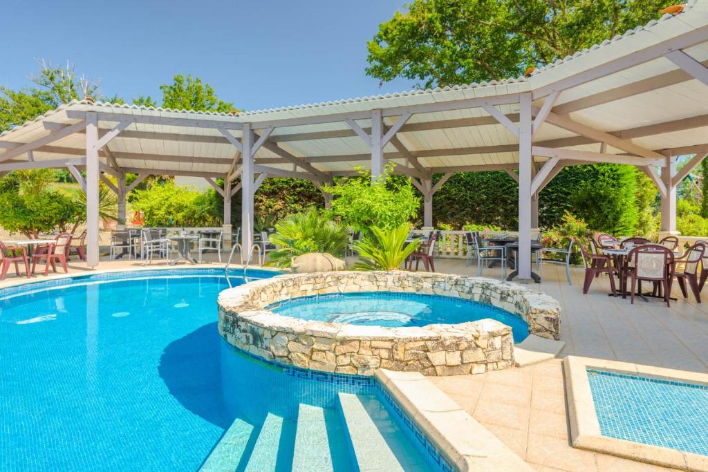 塞格思米尼维伊酒店的一个带凉亭的游泳池和一个带桌椅的庭院。
