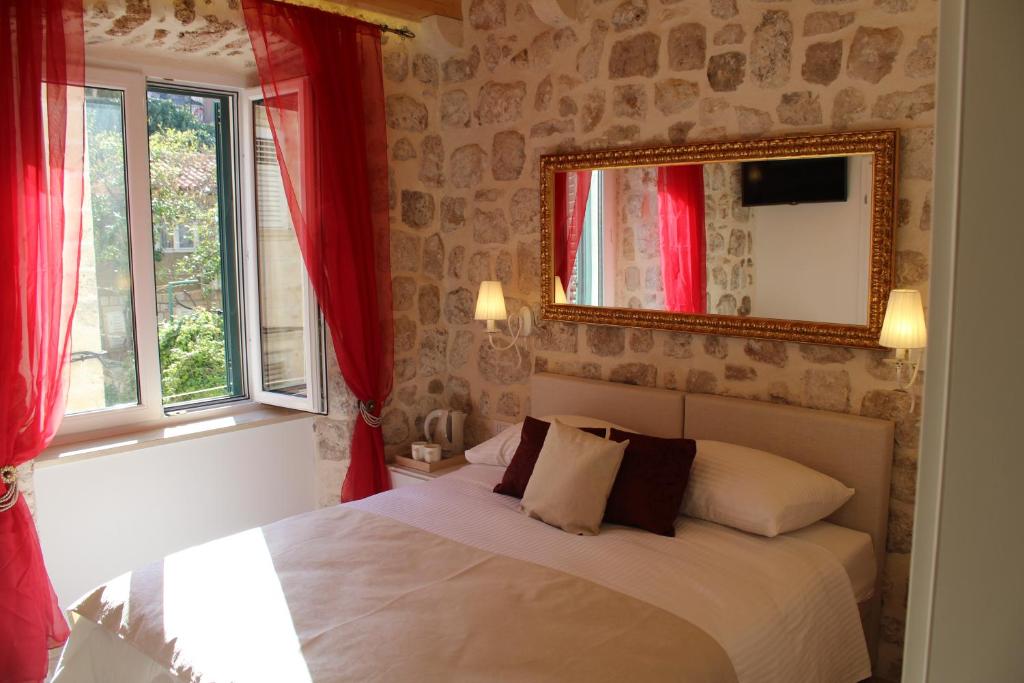 杜布罗夫尼克Villa Sigurata II的一间卧室配有一张带红色窗帘和镜子的床