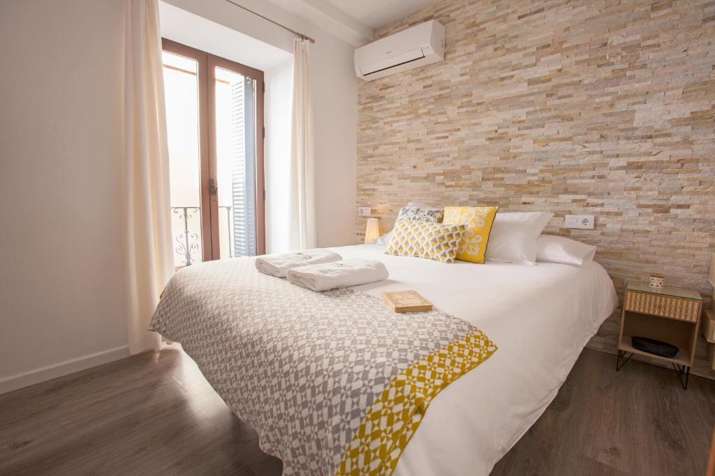 塞维利亚Lukanda Casa de las Especias的一间卧室设有一张带砖墙的大床