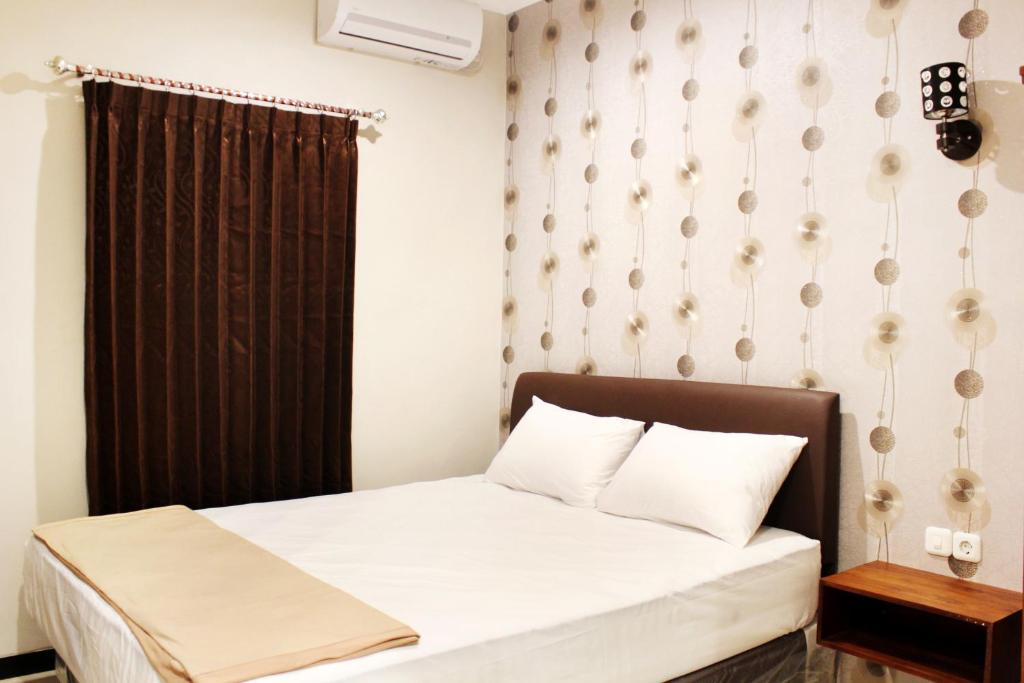 泗水达尔玛万民宿的一间小卧室,配有床和黑色窗帘