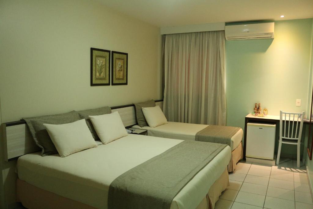 卡鲁阿鲁Hotel Maysa Caruaru的酒店客房配有两张床和一张书桌