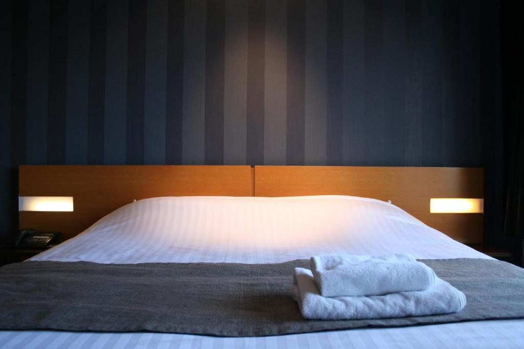 于伊天狼星酒店的一间卧室配有一张床,上面有两条毛巾