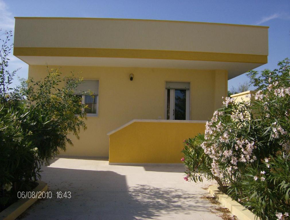 皮佐Villino mare Anita的黄色的房子,有窗户和灌木丛