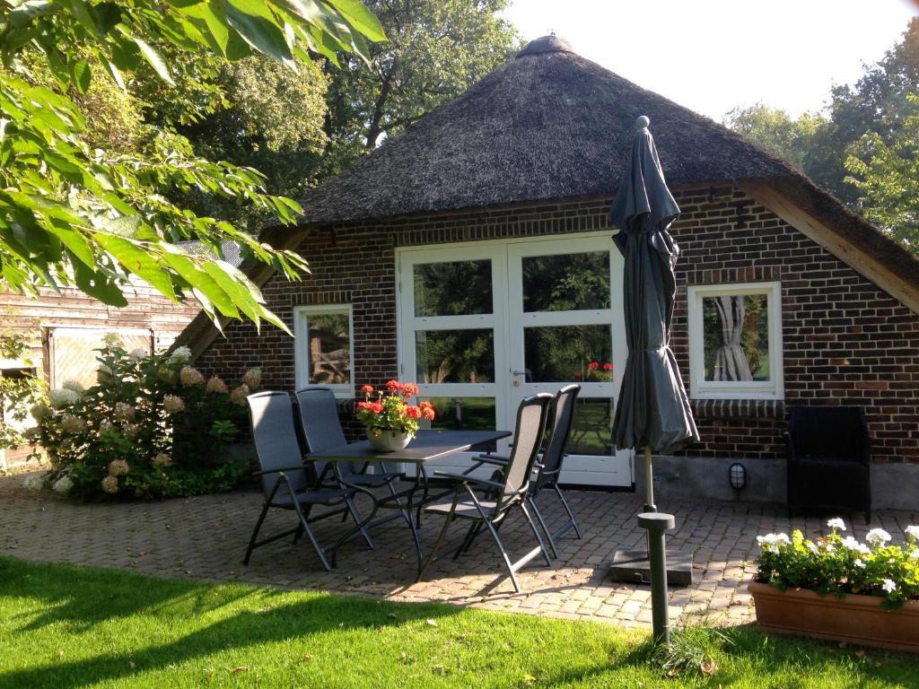兹沃勒Op de Kuyerlatten的庭院配有桌椅和遮阳伞。