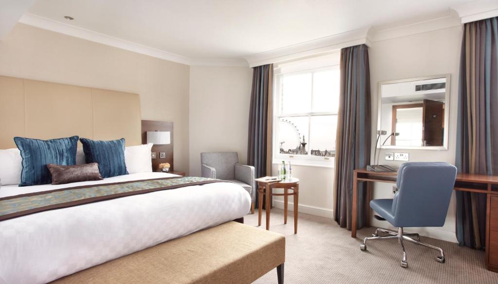 伦敦Thistle London Piccadilly的配有一张床和一张书桌的酒店客房