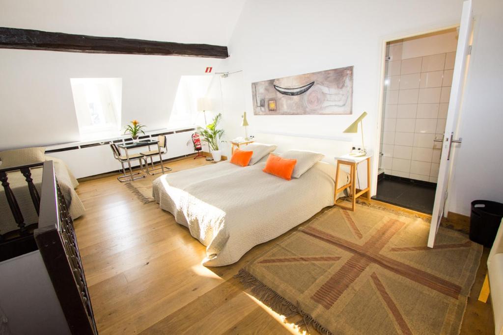 马斯特里赫特迪斯画廊酒店的一间卧室配有带橙色枕头和桌子的床