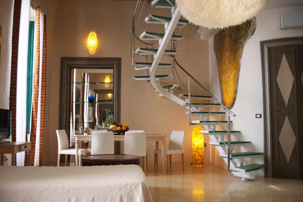 加利波利Palazzo Salapolis - Luxury Apartments的用餐室的螺旋楼梯,配有桌子