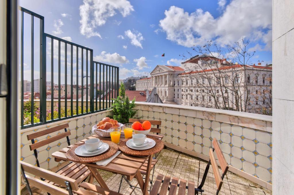 里斯本Jardim Das Flores Luxury Apartment的阳台享有建筑景致,配有桌椅。