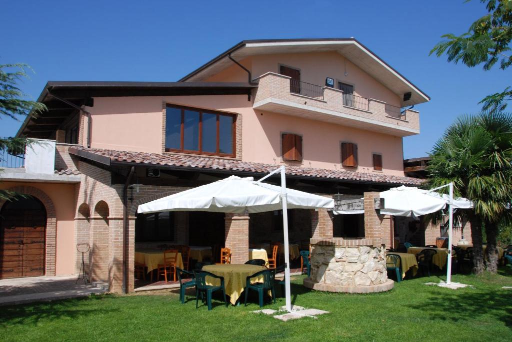 奇维泰拉-德尔特龙托Country House Il Piacere的前面有桌子和遮阳伞的房子