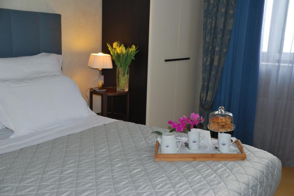 锡拉库扎多莫斯马里阿贝尼西尔酒店的一张带茶杯和鲜花的托盘的床