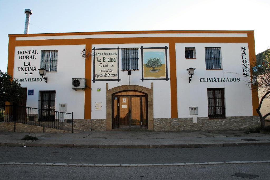 El Real de la JaraHostal la Encina的白色和橙色的建筑,设有门