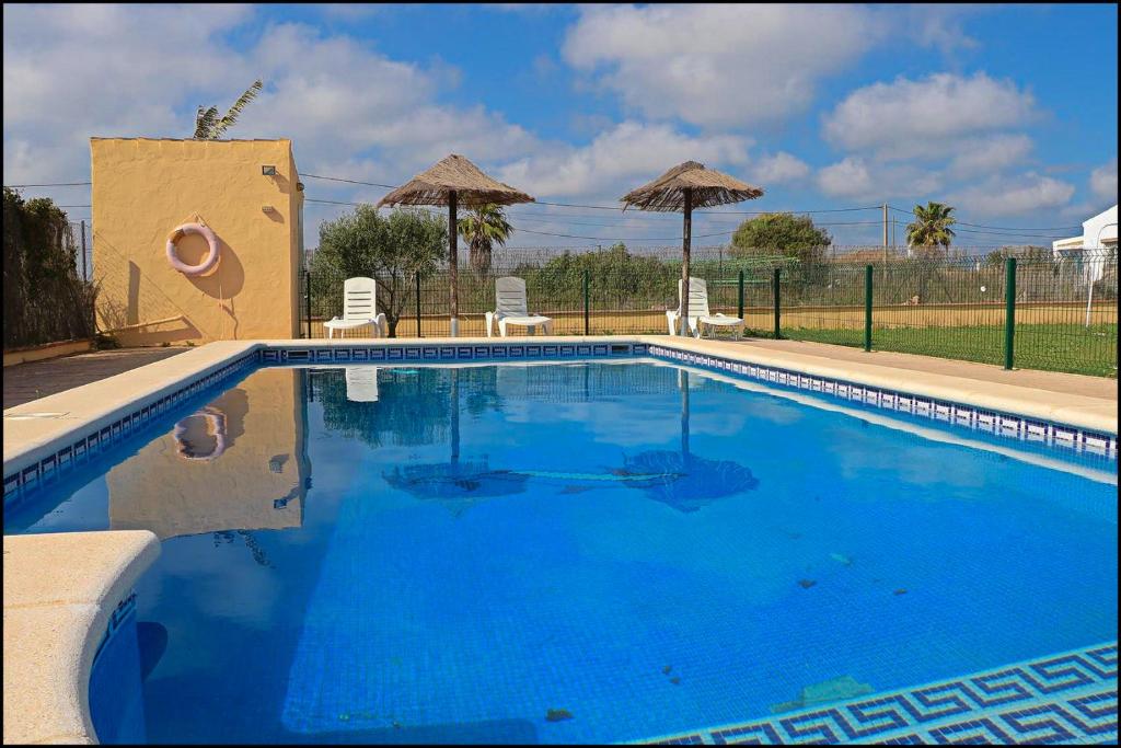 科尼尔-德拉弗龙特拉Bungalow en complejo II的一个带椅子和遮阳伞的大型蓝色游泳池