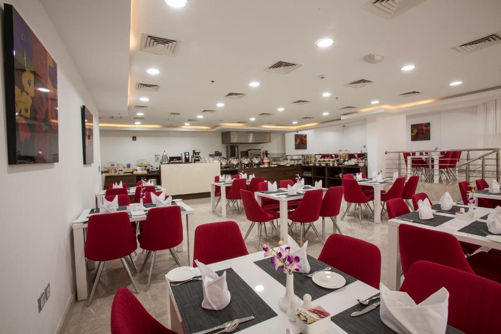 多哈多哈城市酒店的一间设有白色桌子和红色椅子的餐厅