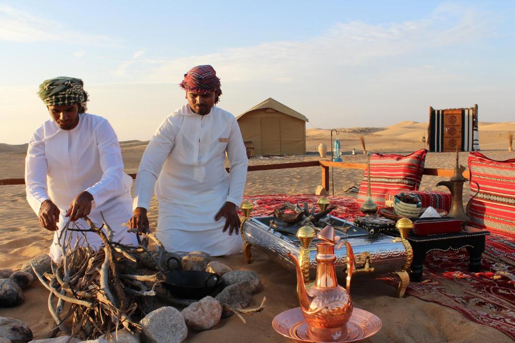 Fulayj al MashāʼikhLegend Desert camp的两个男人站在沙漠的火边
