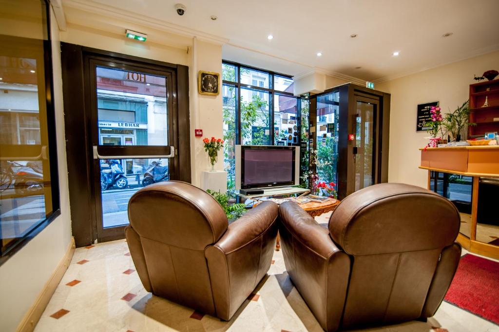 巴黎莱昂纳多达芬奇酒店的客厅配有2把皮椅和电视