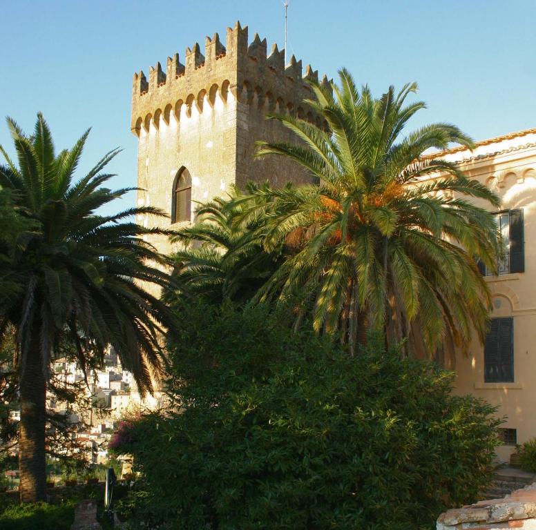 CoriAgriturismo Castello Santa Margherita的一座棕榈树建筑前方的建筑