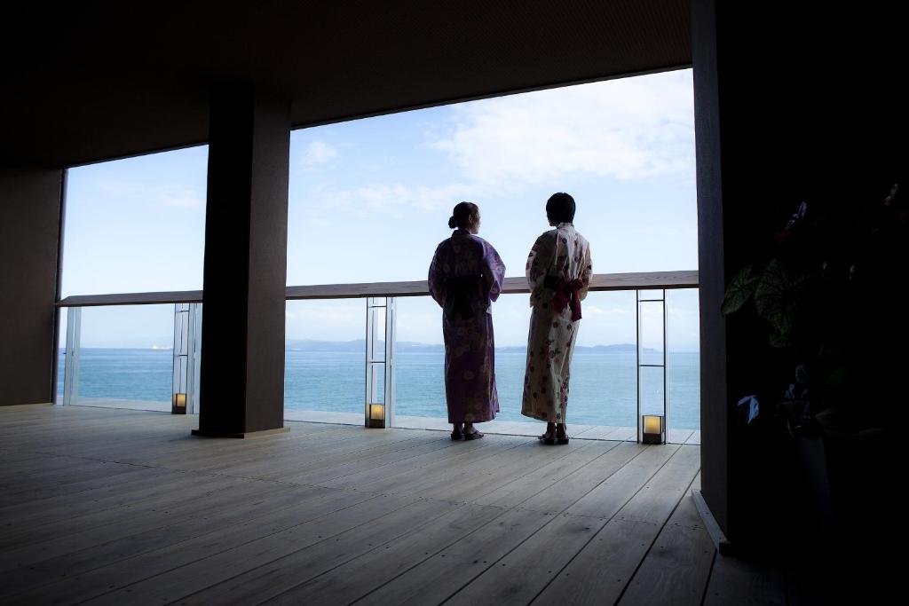 洲本市花历酒店的两人站在一个眺望着大海的阳台