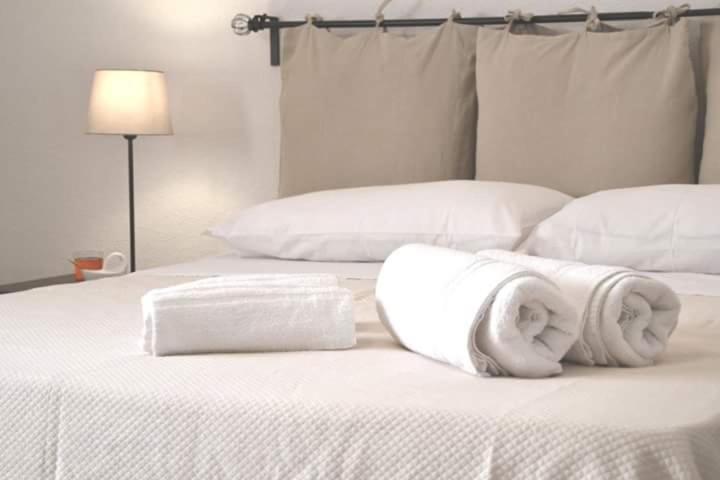 梅林La Frantoiana的一张白色的床,上面有两条滚毛巾
