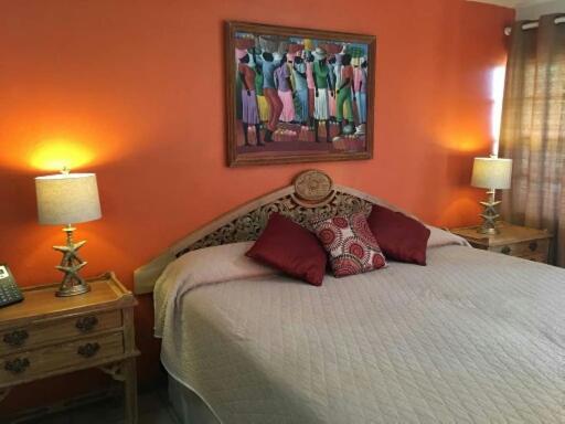金斯敦天堂海滩酒店的一间卧室配有一张带橙色墙壁的床和两盏灯。
