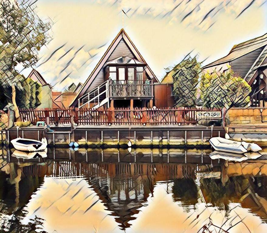 IslehamIsleham River Lodge的水中反射的房子的画
