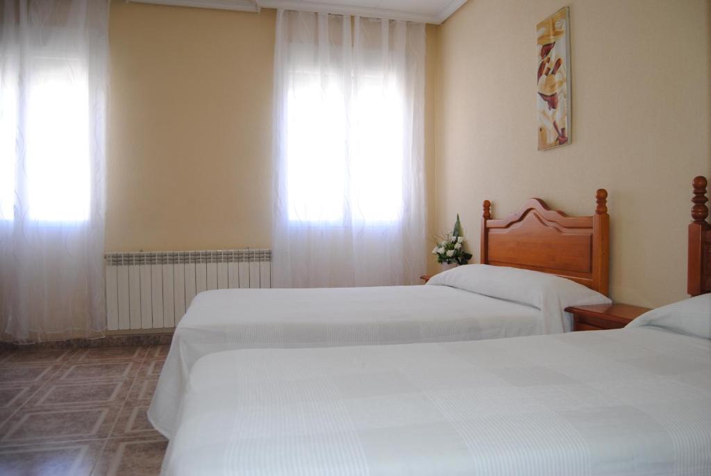 奥卡尼亚Hostal Ávila的一间卧室设有两张床,窗户配有窗帘
