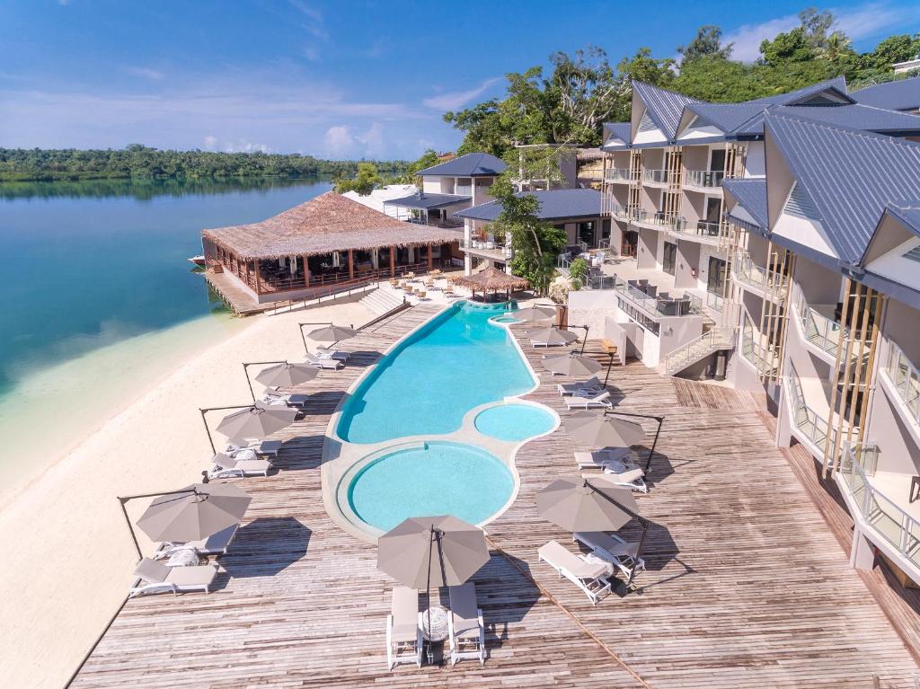 维拉港Ramada Resort by Wyndham Port Vila的享有带游泳池和椅子的度假村的空中景致