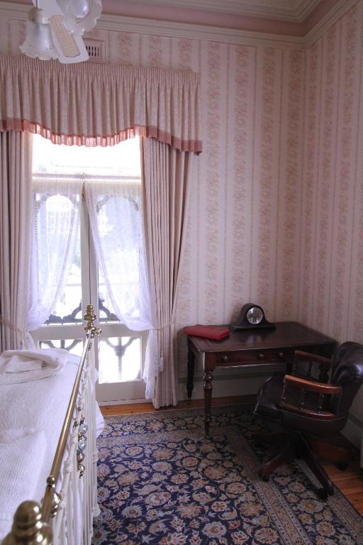 莫尔登棕榈屋住宿加早餐旅馆的一间卧室配有一张床、一张书桌和一个窗户。