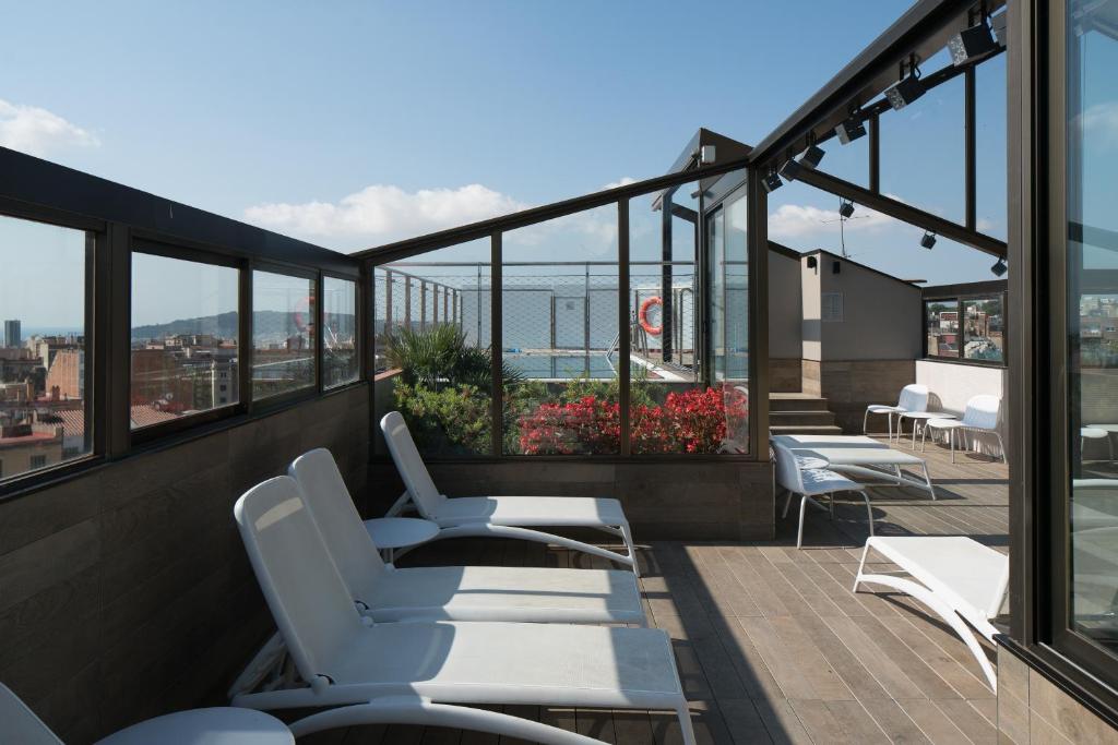 巴塞罗那加泰罗尼亚酒店普特埃特公园店的阳台配有白色椅子,享有海景。