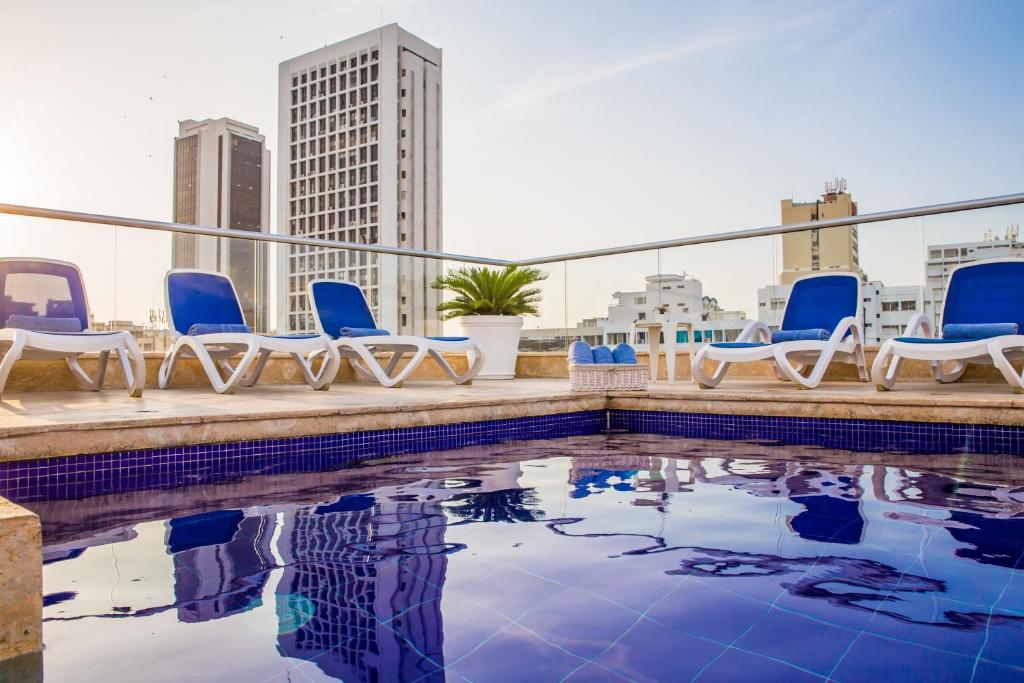 卡塔赫纳炮兵精品酒店的一个带椅子的屋顶游泳池,享有城市美景
