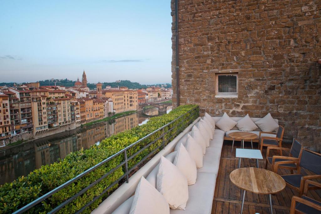 佛罗伦萨Hotel Continentale - Lungarno Collection的砖砌建筑的阳台配有白色枕头和桌子