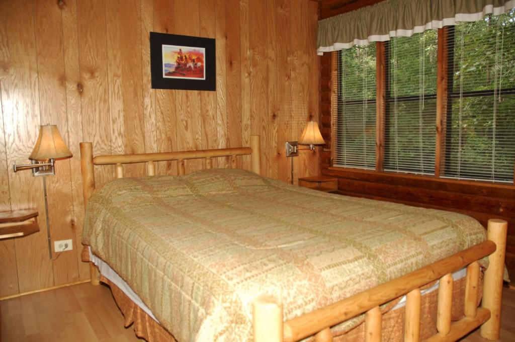 Fair PlayCarolina Landing Camping Resort Cabin 10的卧室配有一张床铺,位于带木墙的房间内