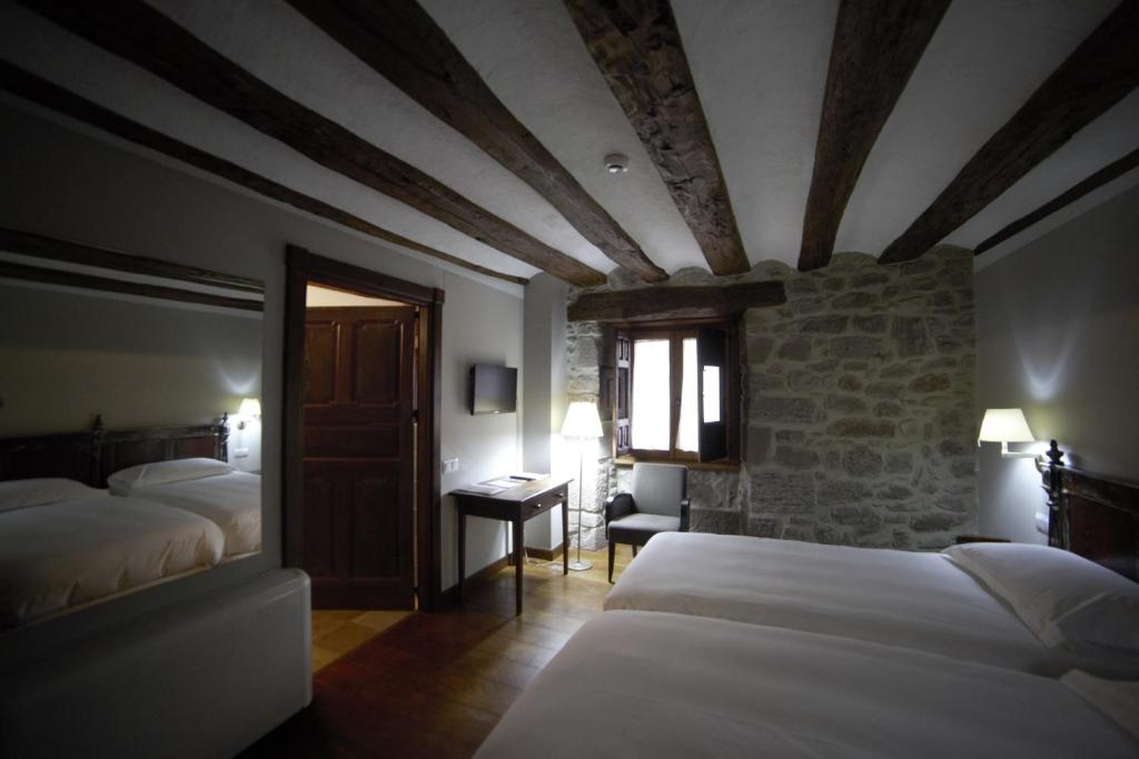 MuesHotel Rural LATORRIÉN DE ANE的一间卧室设有两张床和石墙