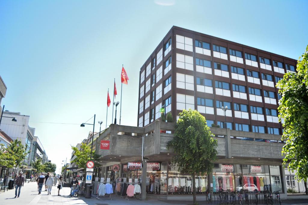 克里斯蒂安桑Thon Partner Hotel Kristiansand的街道上悬挂着旗帜的建筑