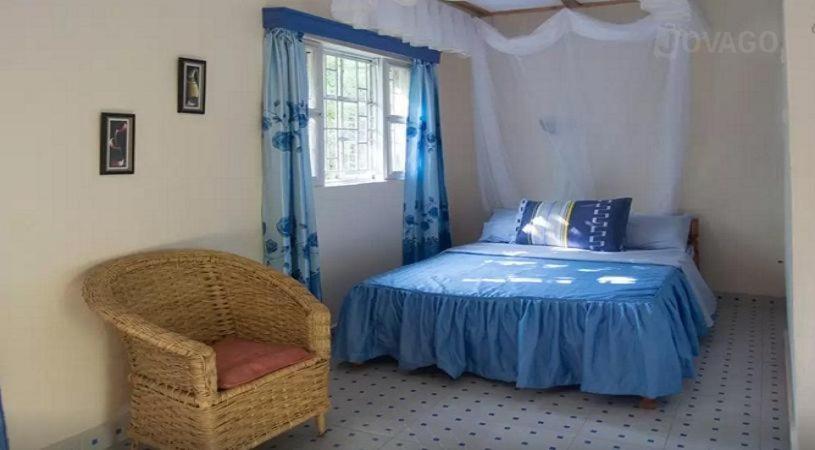 基苏木Ose Cottages的卧室配有床、椅子和窗户。