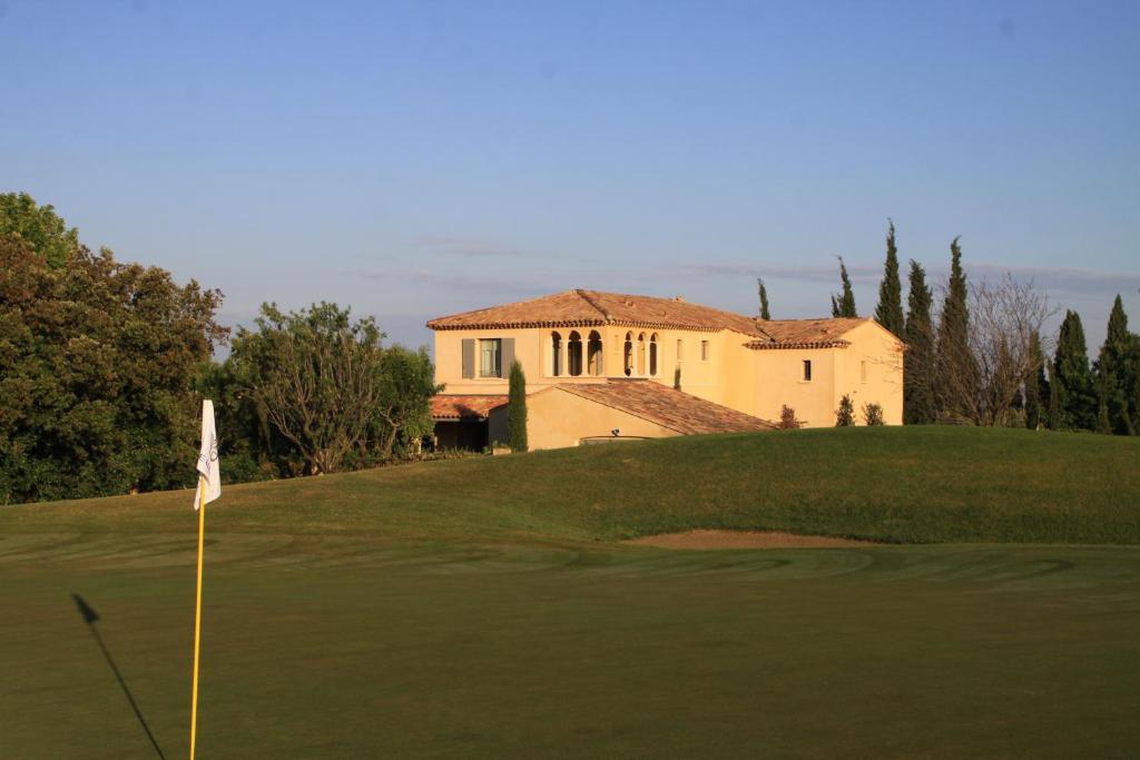马莱莫尔Villa Briali Pont Royal的一座高尔夫球场,后方是一座房子