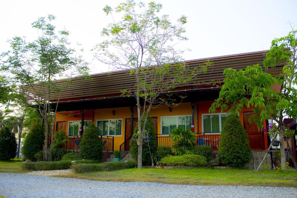 Ban Nong Chang纳维西萨查那莱经济型酒店的一座红黄房子,前面有树木