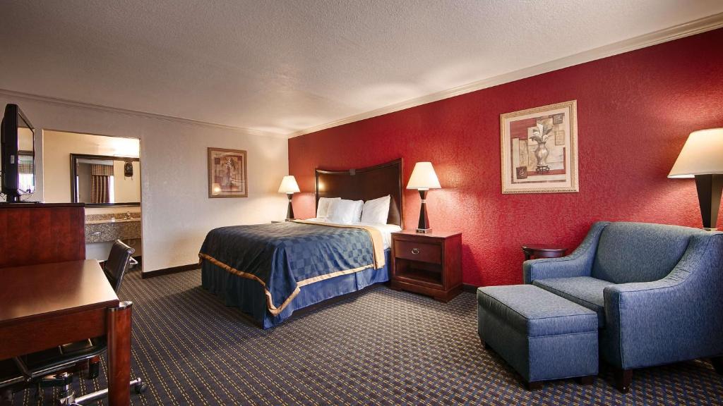 金斯维尔Americas Best Value Inn Kingsville的配有一张床和一把椅子的酒店客房
