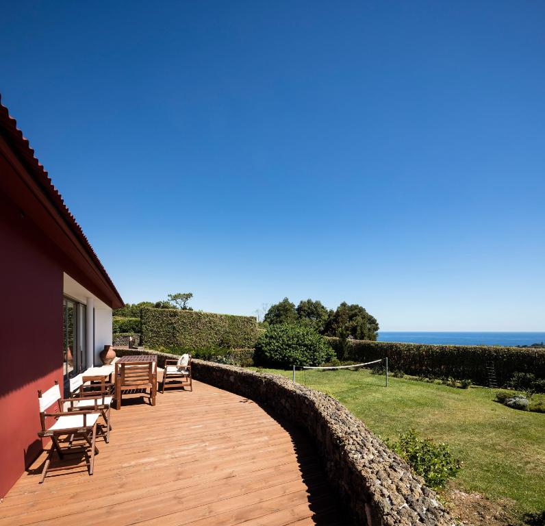 卡佩拉什Quinta da Tilia Boutique Retreat的一个带长椅的木甲板和背景海洋