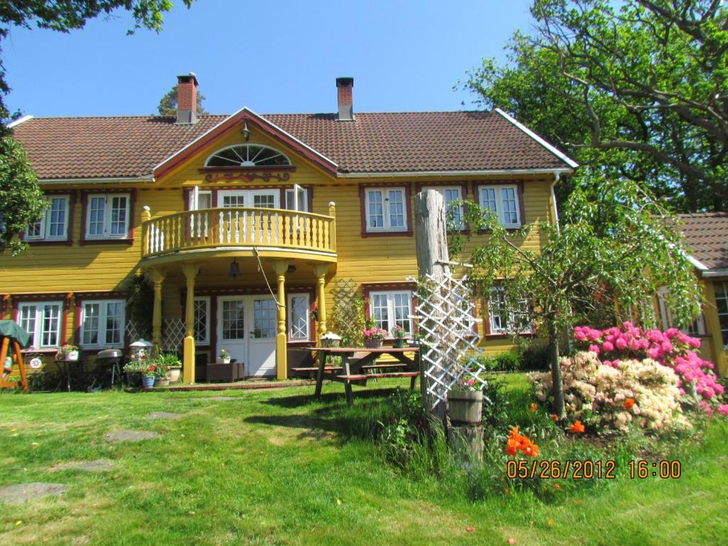 克里斯蒂安桑Bondegårdsparken Farm Holiday的庭院里一座黄色房子,甲板上