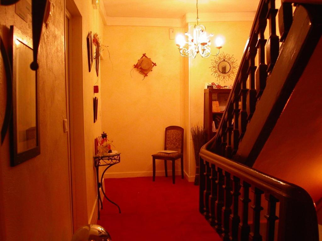 Moulins-la-Marche海豚酒店的走廊设有楼梯、椅子和吊灯