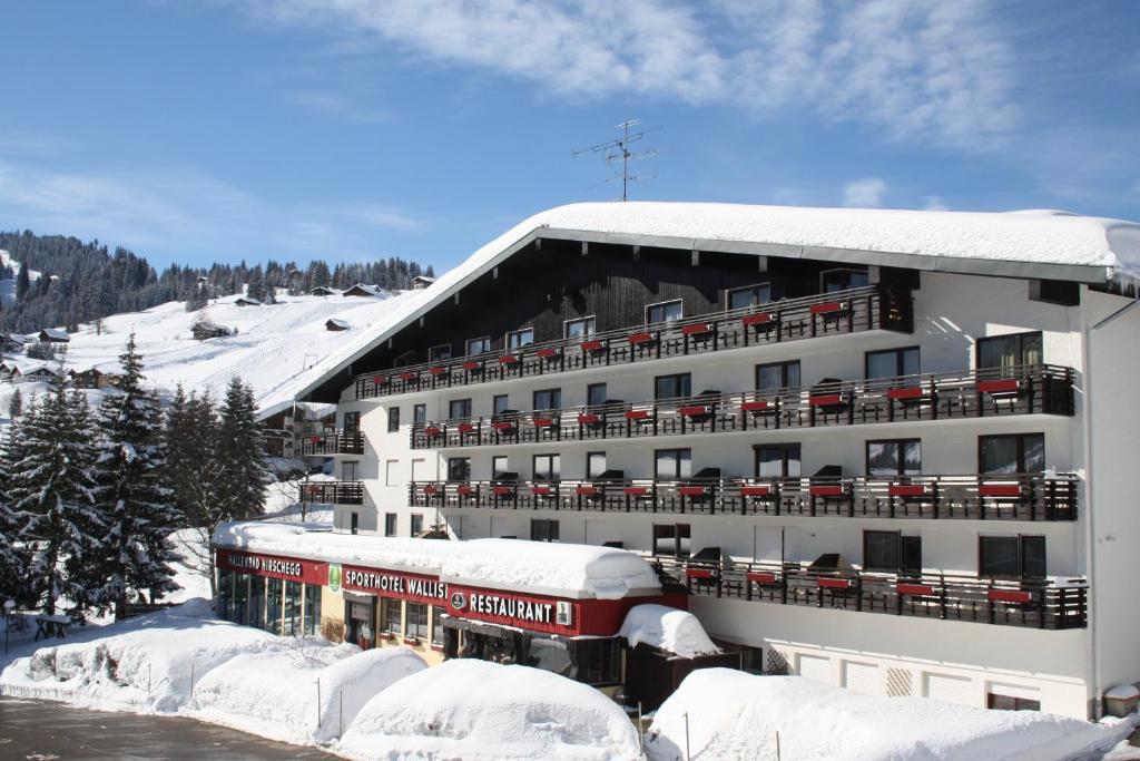 希洛谢克瓦利赛运动酒店的一座有雪盖的建筑,前面有火车
