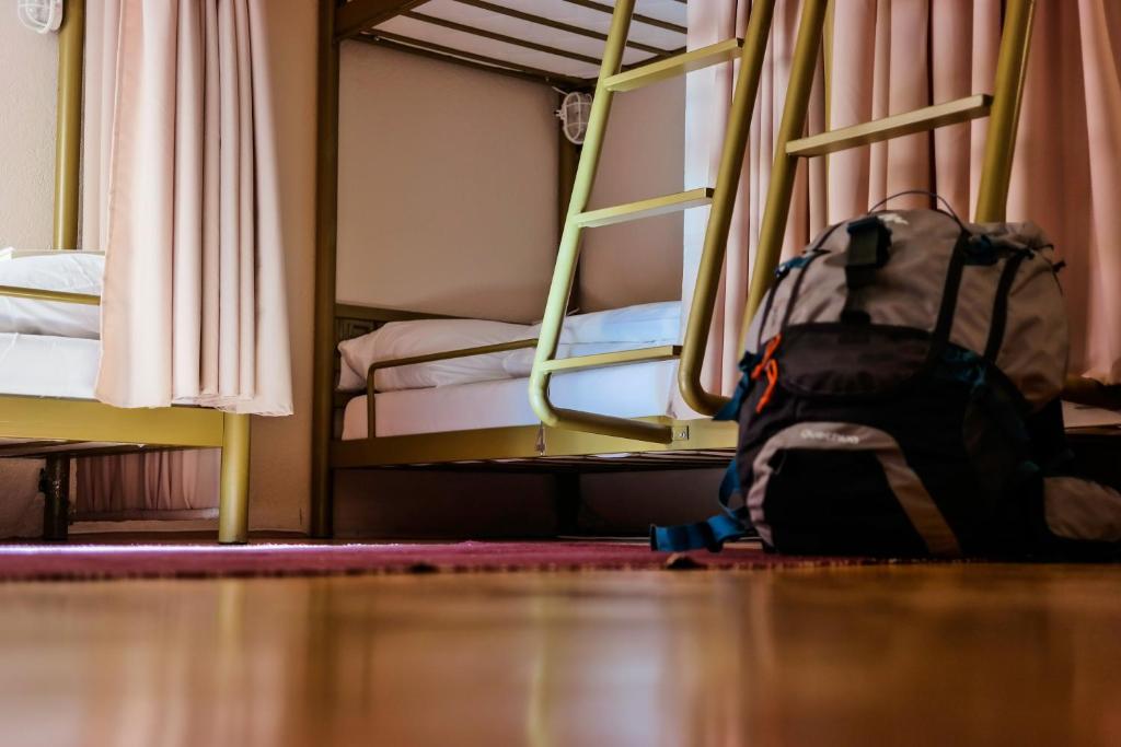 普里什蒂纳ODA Hostel的背包坐在卧室的地板上,卧室配有双层床