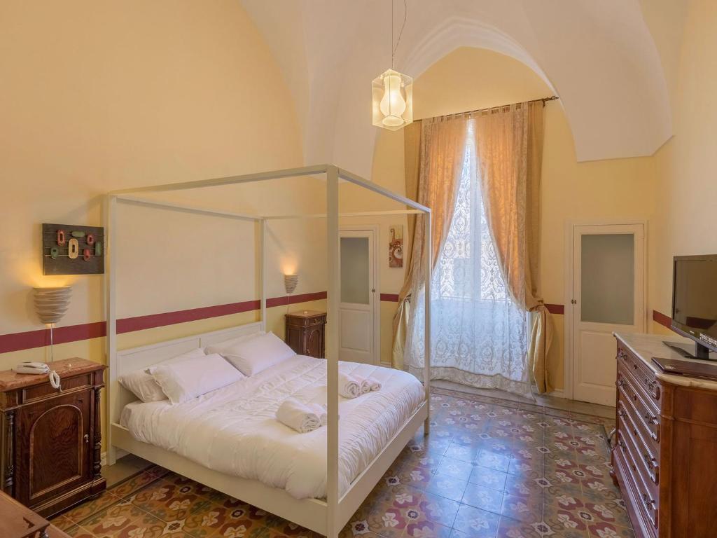 加拉蒂纳La Naca Della Taranta B&B的一间卧室配有一张天蓬床和一台电视机