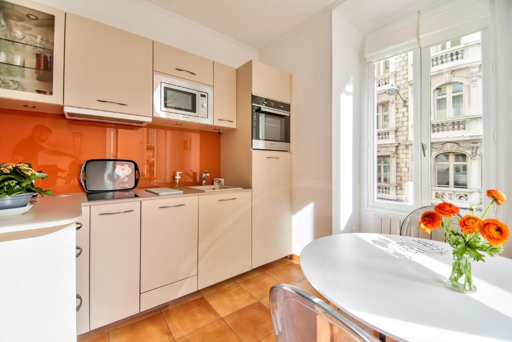 尼斯奥利维特公寓的厨房配有白色橱柜和鲜花桌