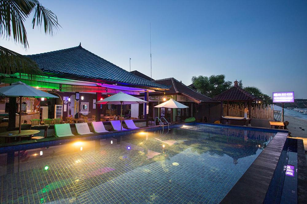 蓝梦岛Linda Beach Hotel的游泳池在晚上提供椅子和遮阳伞