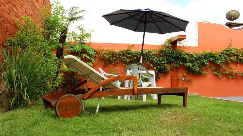 瓜鲁雅Pousada da Ju的草上带雨伞的长凳