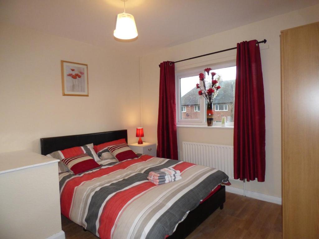 诺丁汉Beckley House的一间卧室配有一张带红色窗帘的床和一扇窗户