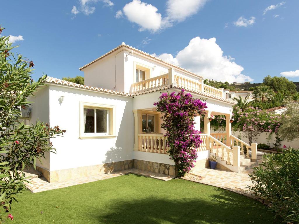 库姆布勒德尔索尔Belvilla by OYO Villa Junique的白色的房子,设有紫色花卉阳台
