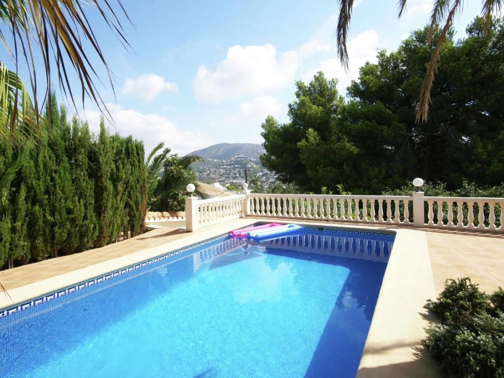 莫莱拉Nice villa in Moraira with private pool and lots of privacy的蓝色的游泳池,拥有白色的围栏和树木