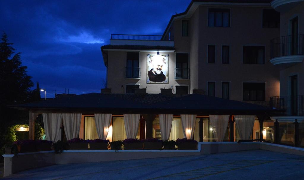 圣乔瓦尼·罗通多Hotel Rosamarina的一座建筑,晚上在它旁边有一个钟